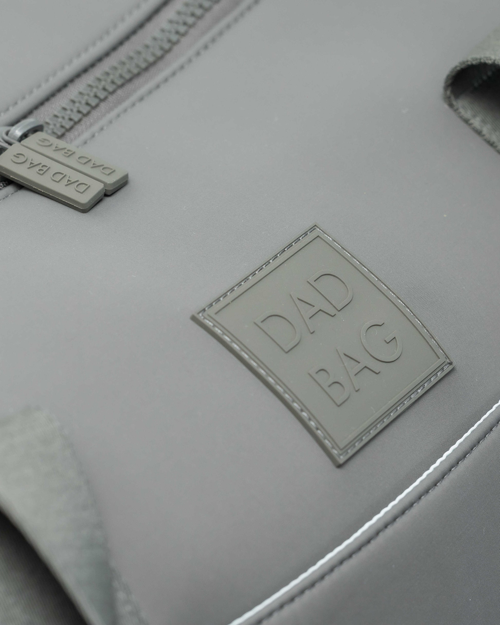 Light gray duffel and hospital bag with 'DAD BAG' label on a neutral background