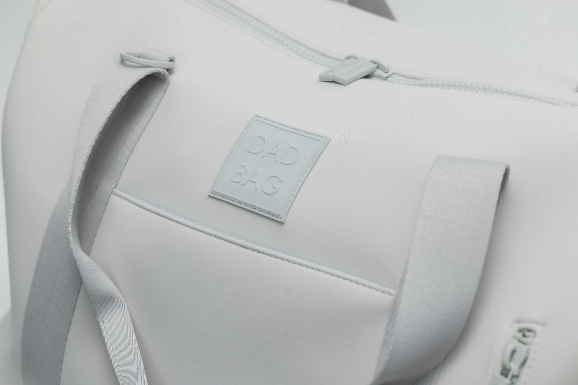 Light gray neoprene bag with a visible dad bag brand label on a light gray background