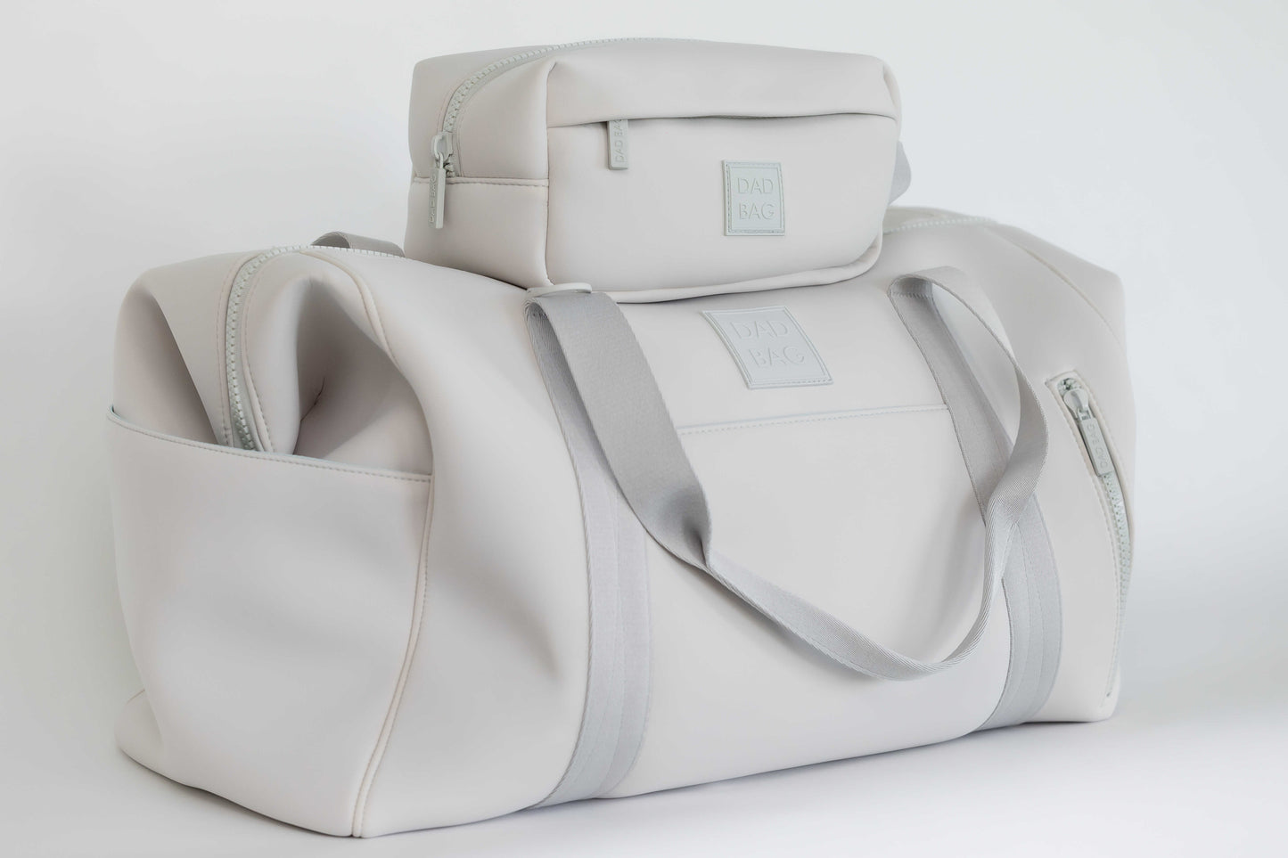 Light gray neoprene hospital and duffel bag with a smaller toiletry bag on top against a white background