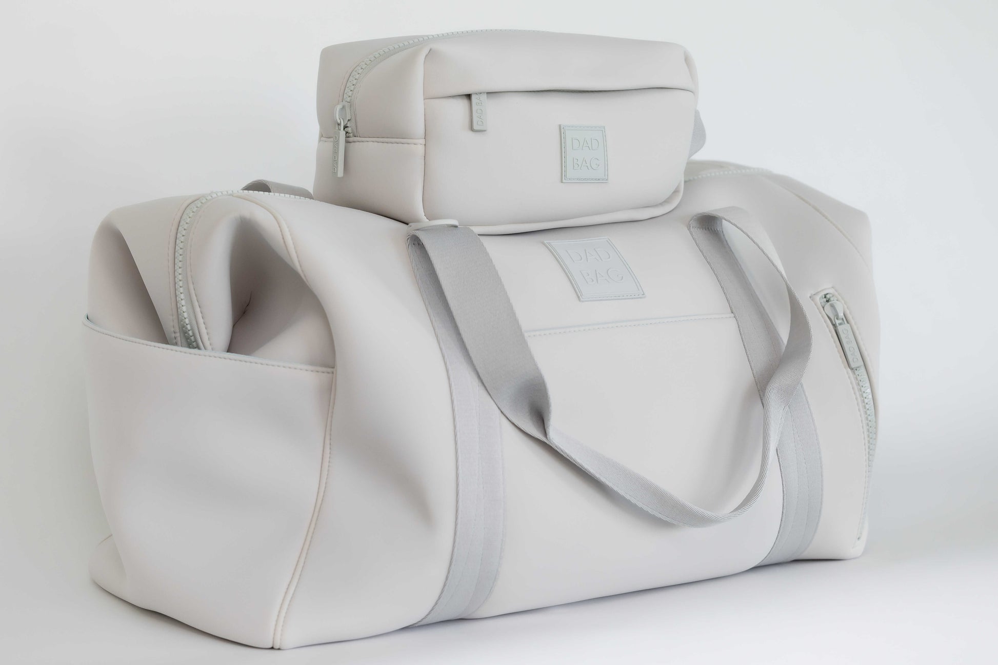 Light gray neoprene hospital and duffel bag with a smaller toiletry bag on top against a white background