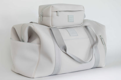 Light gray neoprene hospital and duffel bag with a smaller toiletry bag on top against a white background