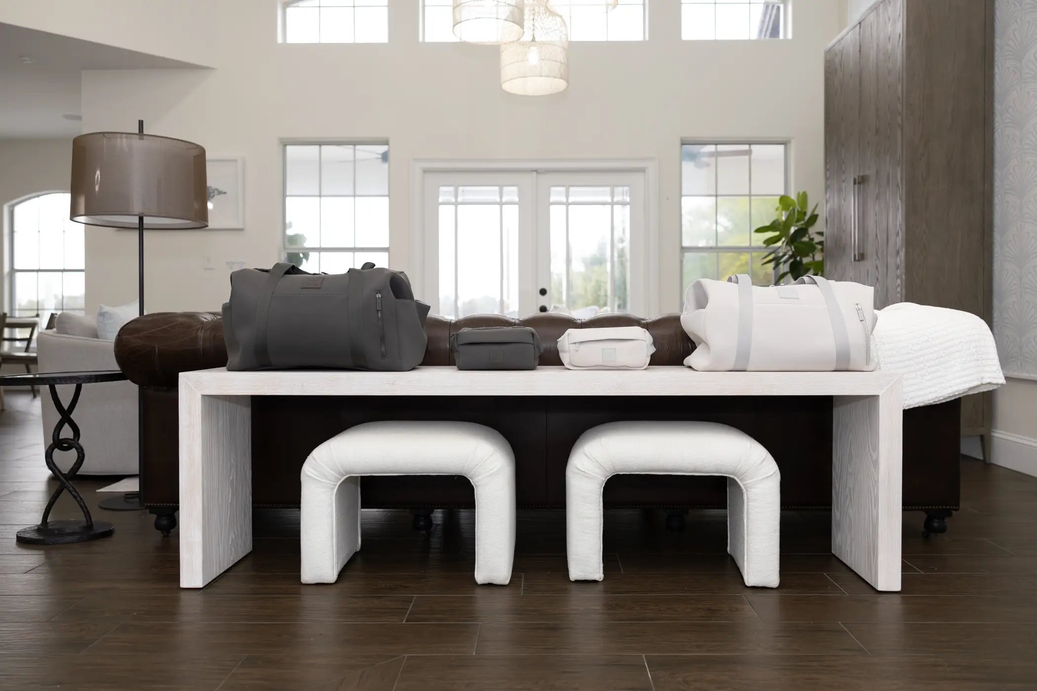 Modern living room with white sofa, ottomans, and a large window